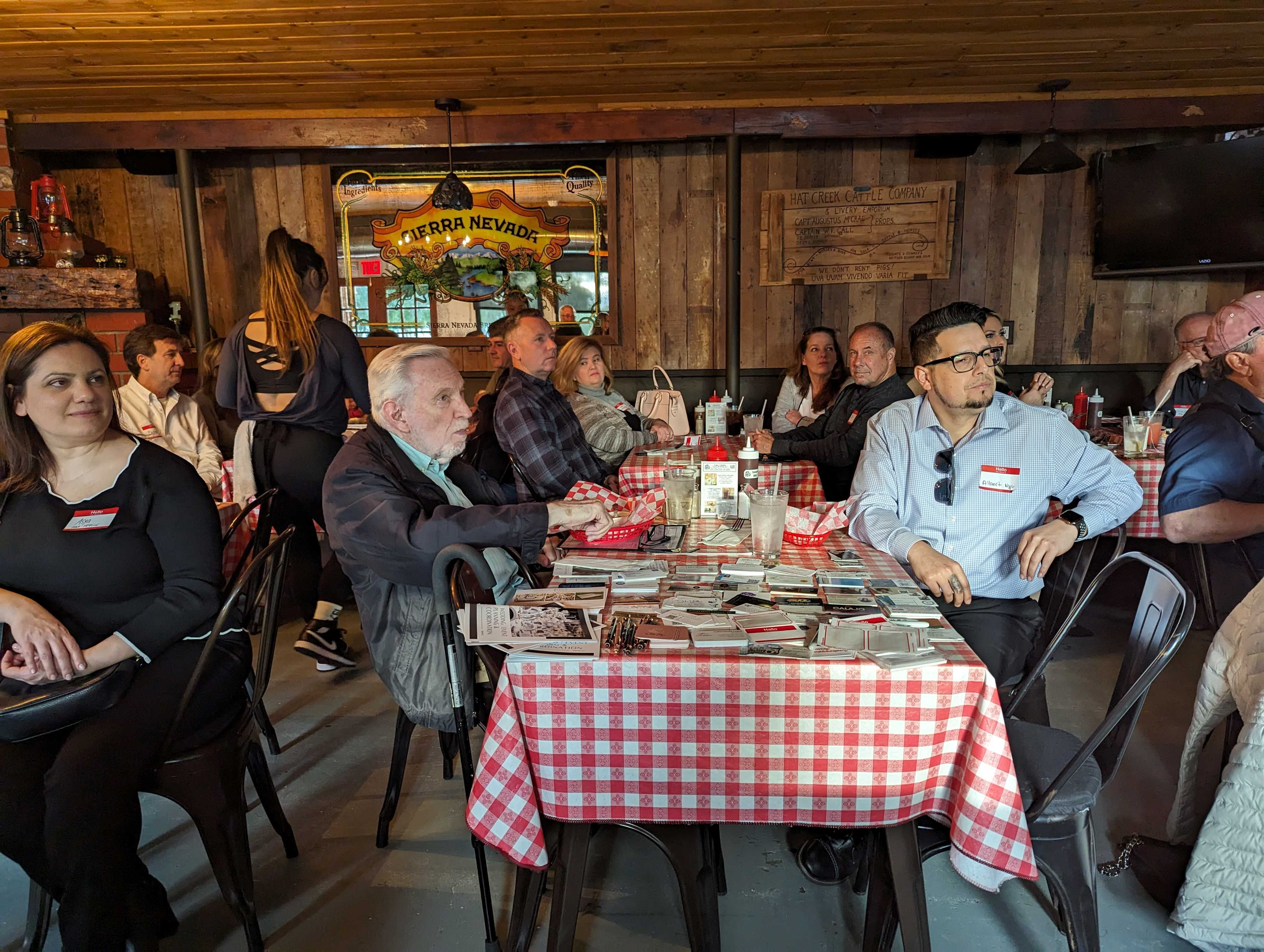 Business peers sitting at a restaurant engaged with speaker at local networking event.